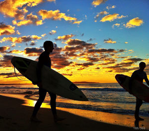 Silhouette of people on beach at sunset