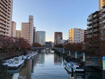 Boats in canal amidst buildings against clear sky