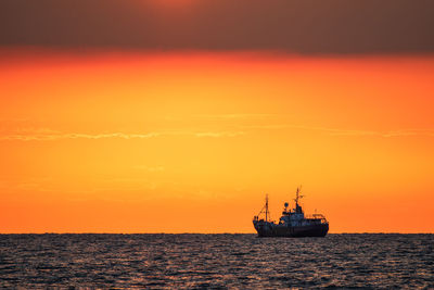 Silhouette ship in sea against sky during sunset