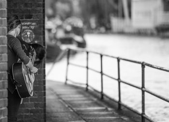 Woman playing guitar at footpath by river