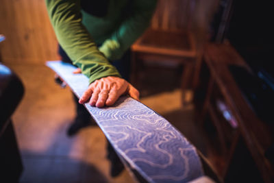 A man applying a skin to the bottom of a ski in a house