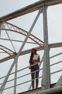 Woman leaning on railing against sky