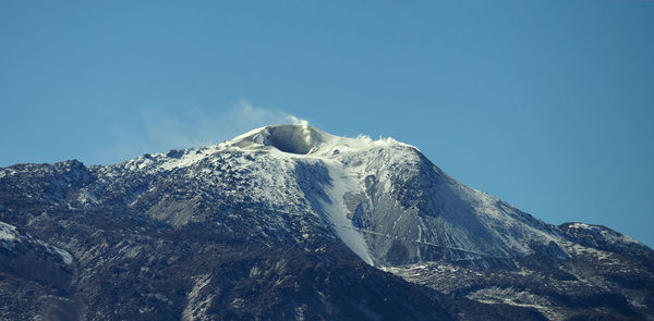 Low angle view of snowcapped mountain against clear blue sky