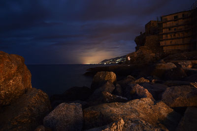 Suggestive view between the rocks of the city of genoa in the distance, with lights and colors