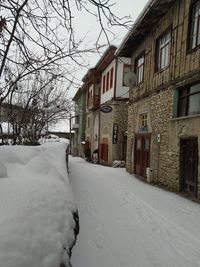 Snow covered houses by buildings against sky