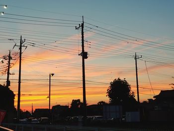 Silhouette electricity pylon against romantic sky at sunset