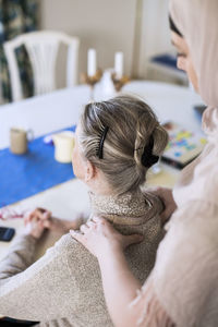 Rear view of young female home caregiver giving shoulder massage to grandmother at home