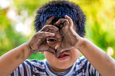 Close-up portrait of boy showing dirty hands