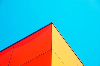 Low angle view of multi colored building against clear blue sky