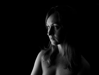 Portrait of young woman against black background