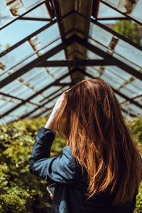 Rear view of woman with arms raised standing outdoors