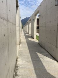 Empty footpath amidst buildings against sky