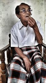 Portrait of man sitting on chair against wall