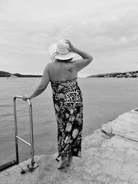 Woman looking at sea shore against sky