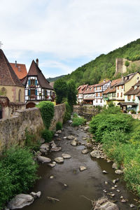 Houses by river amidst buildings against sky