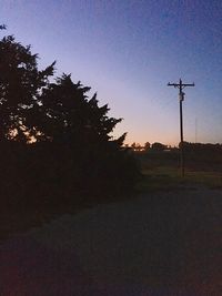 Silhouette trees on field against clear sky