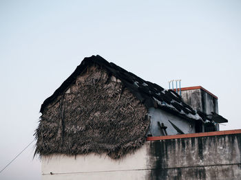 Low angle view of old house roof against clear sky