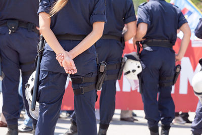 Rear view midsection of police force on street during protest