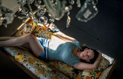 High angle portrait of woman lying on sofa at home