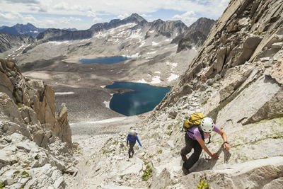 People relaxing on rocks against mountains