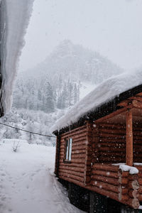 House on snow covered mountain against sky
