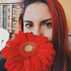 Close-up portrait of young woman with red gerbera daisy