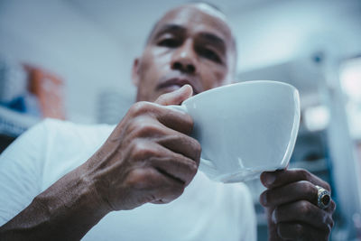 Low angle view of man holding tea cup at home