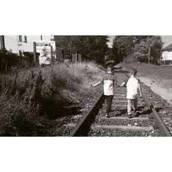 People standing by railroad tracks against clear sky