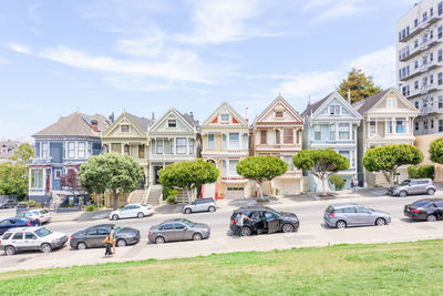 Cars on road by buildings against sky