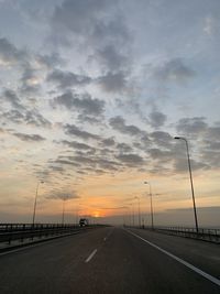 Road by street against sky during sunset