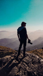 Rear view of man photographing on mountain against sky