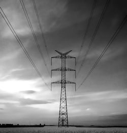 Low angle view of electricity pylon against cloudy sky