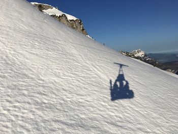 Shadow of person on snowcapped mountain against sky