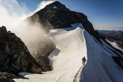Climber traversing a snow ridge whilst mountaineering in new zealand