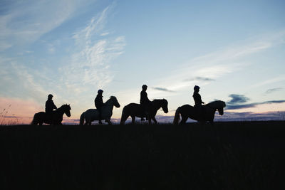 Silhouettes of people riding horses