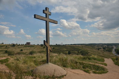 Cross on field against sky