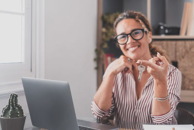 Portrait of smiling woman using smart phone on table