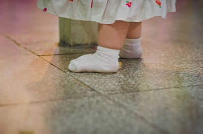 Low section of baby girl standing on tiled floor
