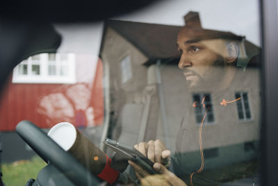 Man holding digital tablet seen through windshield of delivery van