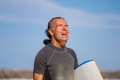 Close-up of smiling man looking away while standing against sky