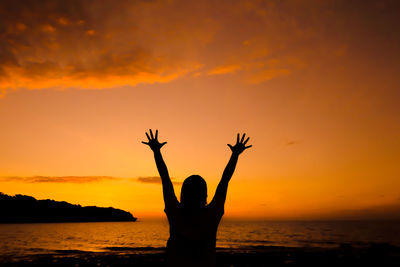 Silhouette person standing by sea against sky during sunset