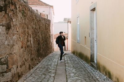 Side view of man on footpath amidst buildings