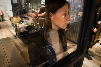 Portrait of woman looking through glass window