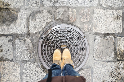 Low section of man standing on manhole