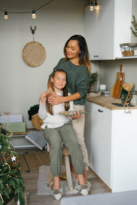 Stylish mom and daughter in homemade clothes eat christmas cookies in the kitchen