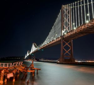 Illuminated bridge over river at night