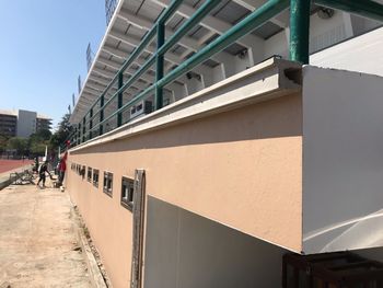 People walking on footpath by building against sky