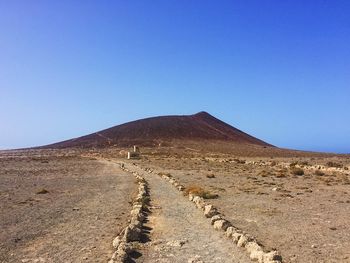 Scenic view of desert against clear blue sky