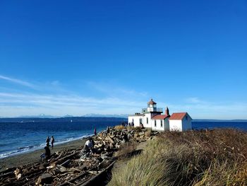 Lighthouse by sea against sky