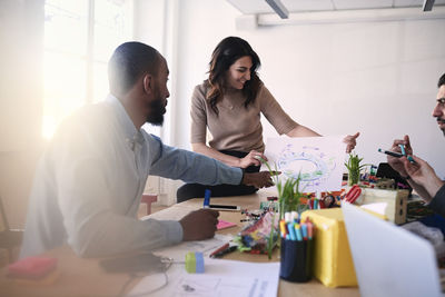 Multi-ethnic male and female engineers discussing over diagram at table during meeting in office